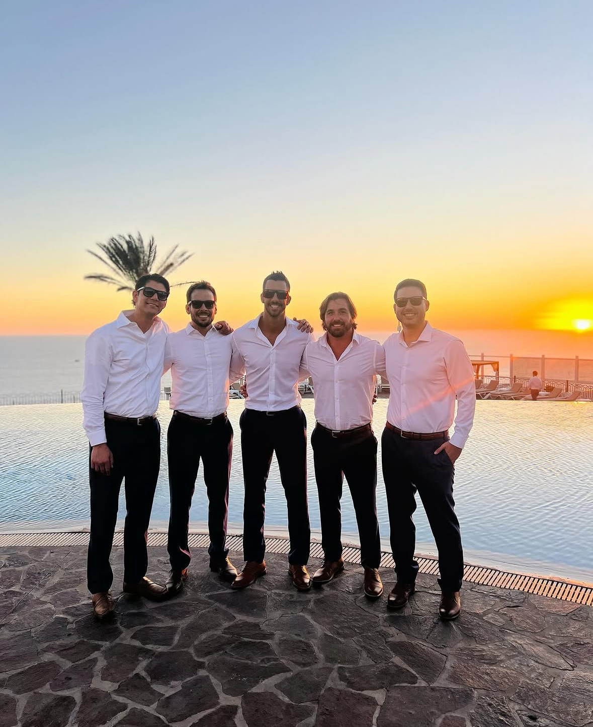Nelson with friends at a wedding by the ocean at sunset
